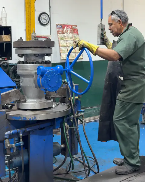 Técnico da BVI operando o volante de uma válvula na bancada de teste